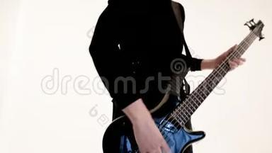 年轻的男音乐家穿着黑色衣服，白色背景上有一把黑色<strong>低音</strong>吉他。 <strong>低音</strong>吉他演奏者演奏音乐